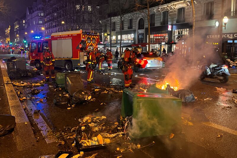 Firefighters extinguish a blaze in the streets of Paris on Monday night. Reuters