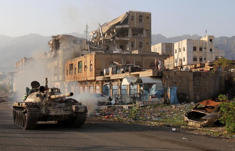 Yemeni fighters loyal to the country's exiled President Abedrabbo Mansour Hadi ride a tank past a destroyed building during clashes with Shiite Huthi rebels in the country's third-city of Taez on May 30, 2019. Taez, in southern Yemen, is under siege by the Huthis but controlled by pro-government forces, who are supported by the military coalition led by Saudi Arabia and the United Arab Emirates. / AFP / Ahmad AL-BASHA
