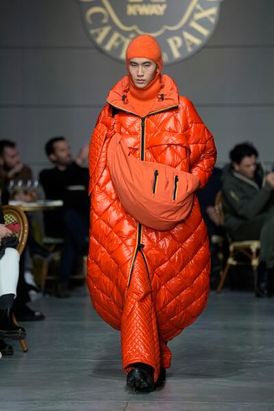 A long puffer coat, enveloping the model as a sleeping bag, and in the brand's traditional orange, at K-Way menswear autumn/winter 2023-2024 show. AP Photo