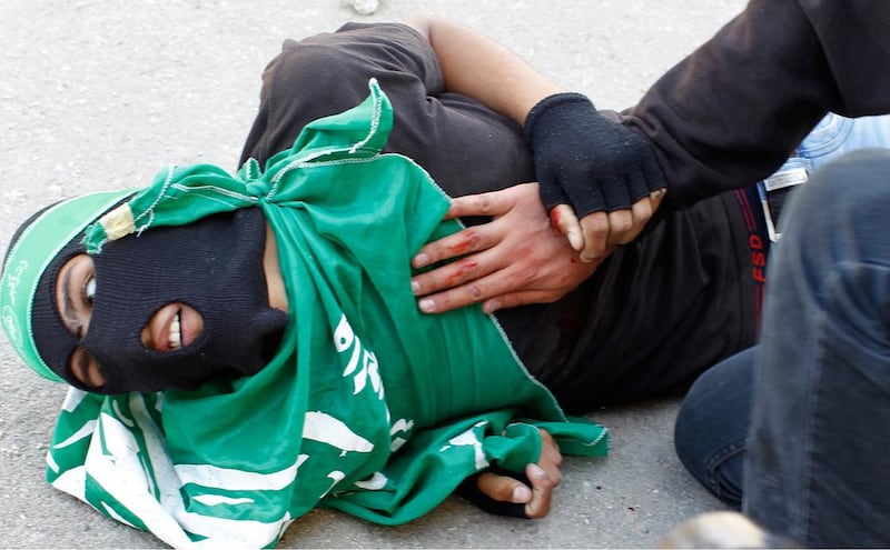 Mohammed Salaheh, 16, lying on the ground after being shot by Israeli forces during clashes following a protest outside the Israeli-run Ofer prison on May 15, 2014. Abbas Ninabu / AFP Photo