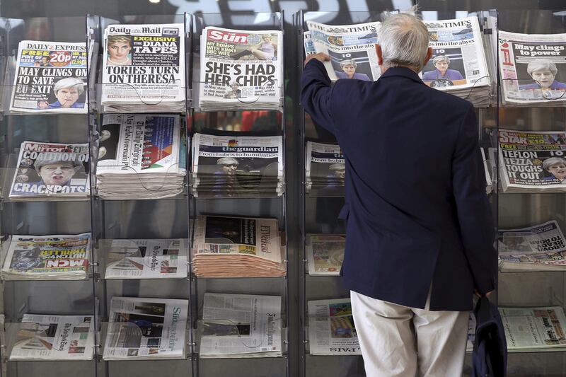 A man picks up a newspaper reporting the development following Britain's general election at a shop in Westminster in London. Tim Ireland / AP Photo