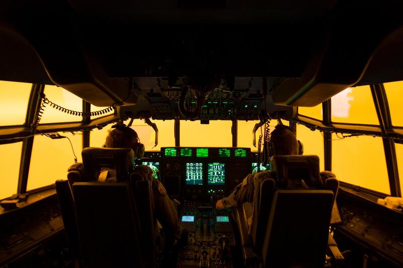 The flight deck of a C-130J Hercules aircraft has a warm glow from wildfires, as the pilots prepare to land at Merimbula airfield to deploy Fire and Rescue crews.  AP