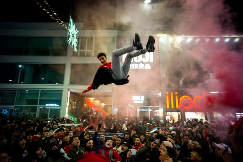 A young man is thrown in the air by Moroccan supporters as part of celebrations in Milan, Italy. AP