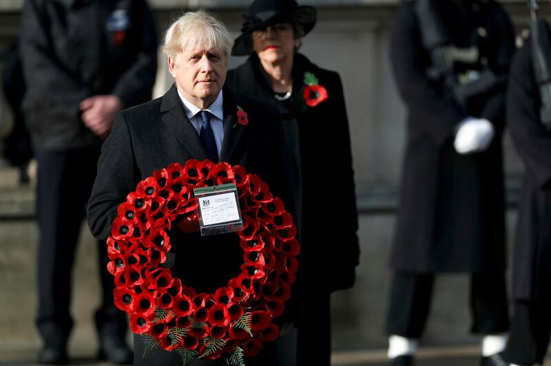 FILE - Britian's Prime Minister Boris Johnson carries a wreath, during the Remembrance Sunday service at the Cenotaph, in Whitehall, London, Sunday Nov. 8, 2020. Johnson says Britain and the United States will work together to support democracy and combat climate change. He denies that his close ties to President Donald Trump would hurt U.K.-U.S relations once President-elect Joe Biden takes office in January.  (Peter Nicholls/Pool Photo via AP, File)