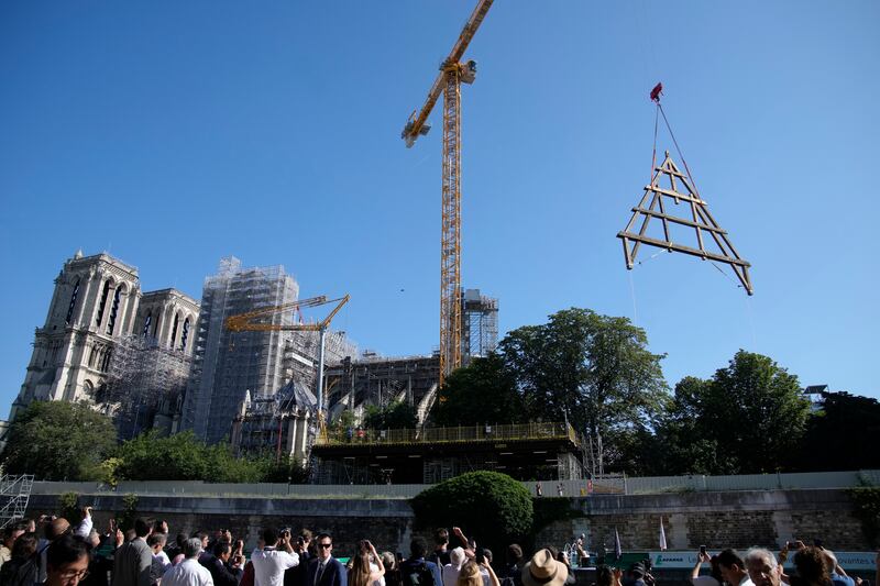 A crane lifts a huge oak frame at Notre Dame de Paris cathedral, Tuesday, July 11, 2023 in Paris.  The panels are due to be reassembled on the top of Notre Dame to replace the roof that flames turned into ashes in 2019.  (AP Photo / Christophe Ena)