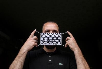 epa08465898 A man puts on a protective face mask made by Nabil Saber Abu Ghabin with the checkered cotton cloth he normally uses to make the traditional Palestinian keffiyeh at his workshop in Gaza City, 04 June 2020. The 60-year-old tailor has reoriented his production to manufacture face masks that are exported to Europe, where they are used for protection against infection with the SARS-CoV-2 coronavirus that causes the pandemic COVID-19 disease.  EPA/MOHAMMED SABER