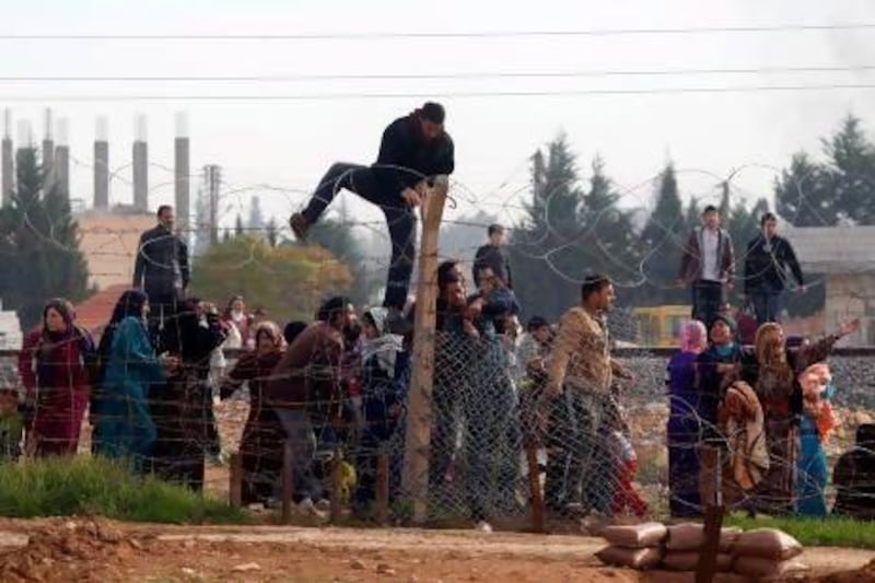 Syrians try to cross the border from their town of Ras Al Ain to the Turkish border town of Ceylanpinar after an air strike.
