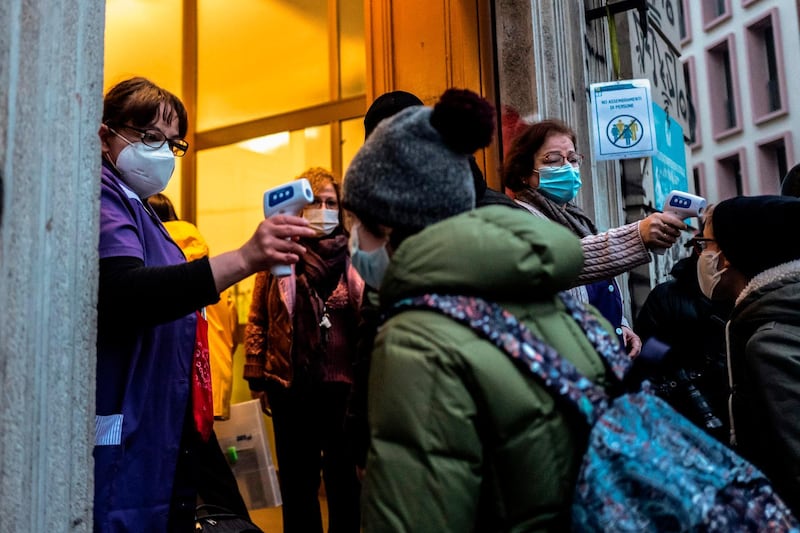 Caretakers check the temperature of students at the entrance of the Italo Calvino school in Turin.  From January 7 primary school and secondary school students are returning to school with 50% capacity. AFP