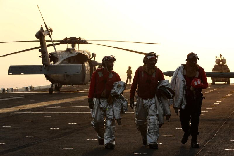 Firefighters walk away after the landing of an MH-60S Sea Hawk.