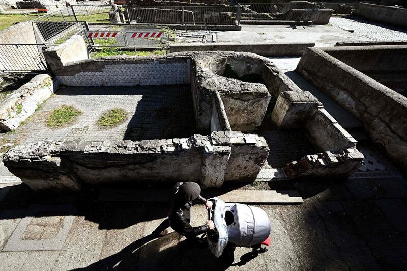 A man pushes a pram as he walks along the Foro Traiano Roman ruins in Rome. AFP