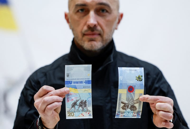 Governor of the National Bank of Ukraine Andriy Pyshnyi holds banknotes marking the first anniversary of Russia's invasion on Ukraine, in Kyiv. Reuters