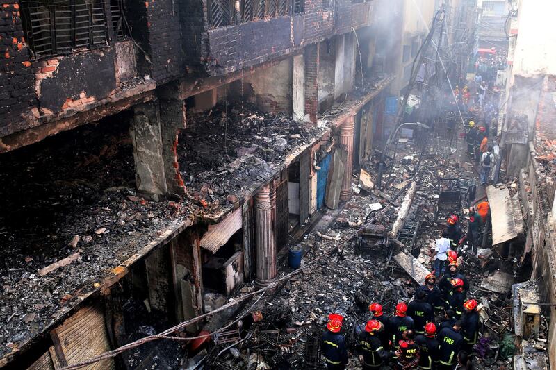 Locals and firefighters gather around buildings that caught fire late Wednesday in Dhaka, Bangladesh, Thursday, Feb. 21, 2019. A devastating fire raced through at least five buildings in an old part of Bangladesh's capital and killed scores of people. (AP Photo/Rehman Asad)