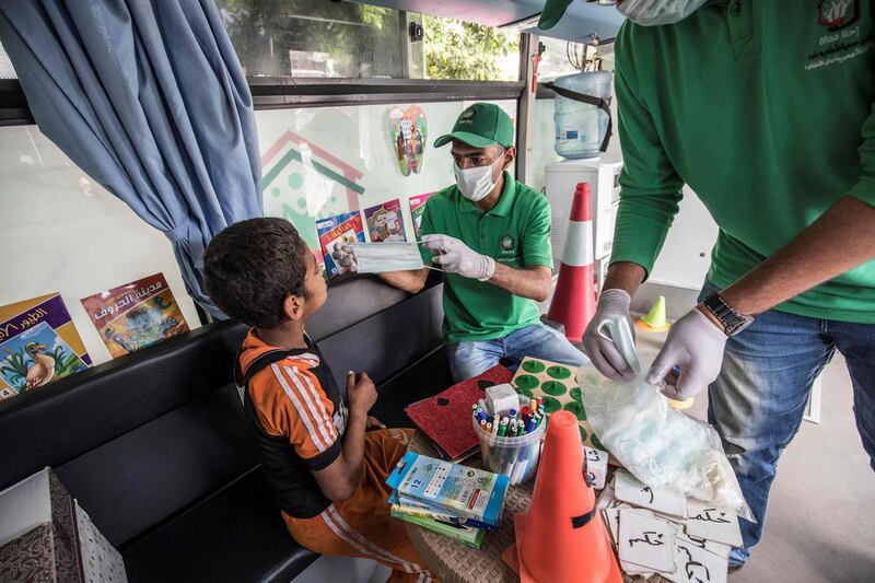 A social worker shows a homeless child the proper way to use a face mask inside one of the mobile units run by the Egyptian authorities, in Abbasia district of the capital Cairo.  AFP