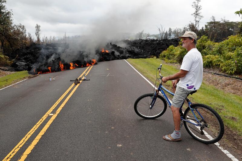 Leilani Estates resident Sam Knox watches the lava stretch across the road in Pahoa, Hawaii. Knox's home is less than a few hundred yards from the lava flow and he does not have any plans to evacuate. Knox is hopeful the lava will not take his home. Marco Garcia / AP Photo
