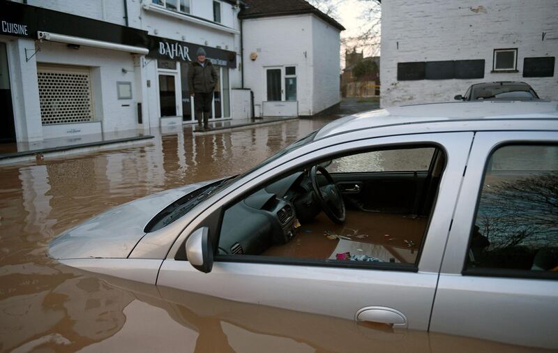 Flood water surrounds abandoned cars left in a flooded street in Tenbury Wells, after the River Teme burst its banks in western England.  AFP
