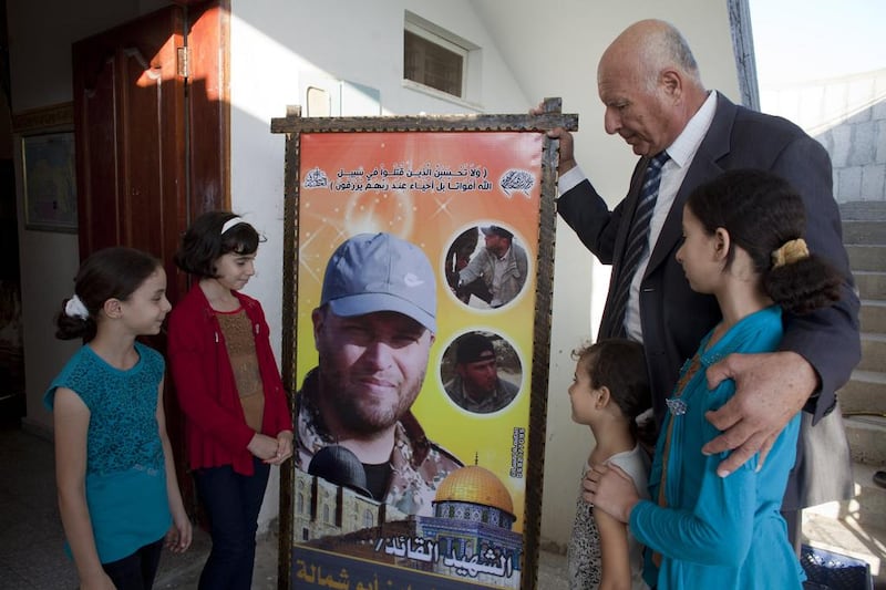 Fayez Abu Shammala, 63, with his children, holds a poster of his 32-year-old son Hazem, who he only discovered after his death that he was a fighter in in the Islamic Jihad. Hazem was killed by a mortar shell while fighting Israeli soldiers in the eastern Qarrarah area near the southern city of Khan Younis, Mr Abu Shammala said. Heidi Levine for The National

