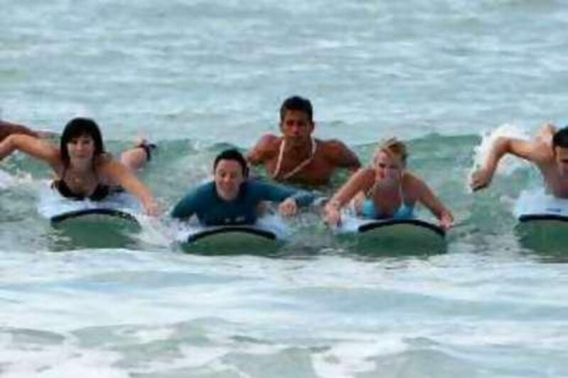 DUBAI, UNITED ARAB EMIRATES – Dec 7: Scott Chambers (centre), MD of Surf Dubai teaching students how to surf at Jumeirah beach in Dubai. (Pawan Singh / The National) *** Local Caption ***  PS04- SURFING.jpg