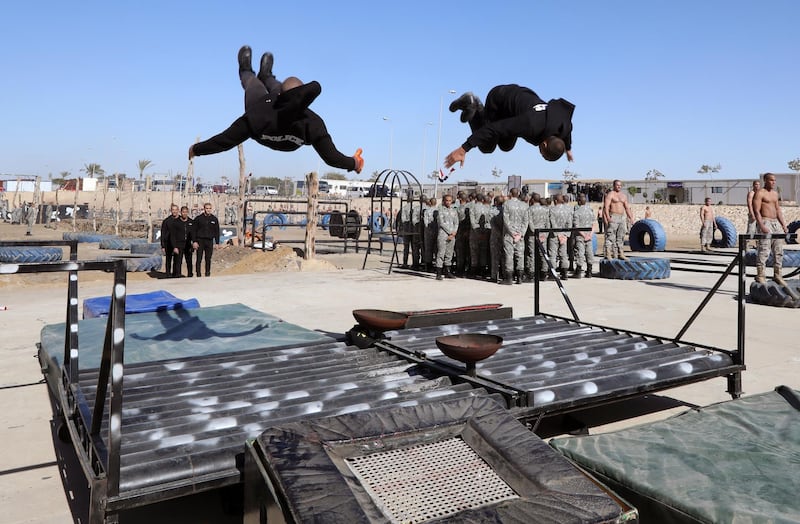 Egyptian police perform somersaults over an obstacle.