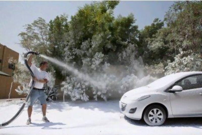 Ben Elliott-Scott, managing director of Desert Snow, sprays a typical street side scene in Jumeirah with artificial snow typically used on movie sets and stages. ANTONIE ROBERTSON / The National