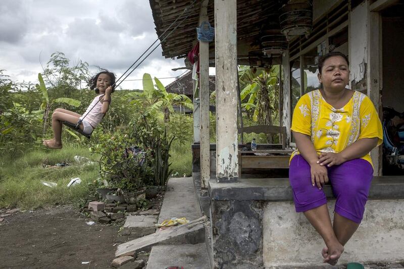 Fitriani, and her daughter Azizah, play in front of their house which was partially destroyed by the mudflow when it hit Merisen Village. Ten years on, more than 100 families have yet to receive compensation. Ulet Ifansasti / Getty Images