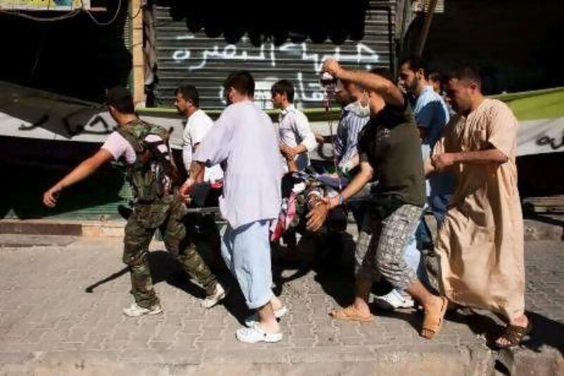 A Syrian rebel (left) helps men carry a civilian wounded by sniper fire to a hospital in the northern city of Aleppo. Fighting in Aleppo, only 50 kilometres from the border, has swelled the number of refugees fleeing to Turkey.