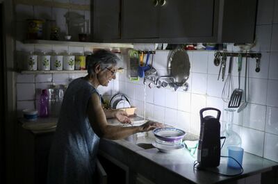 Samira Hanna, 70, washes dishes in her kitchen as she uses a portable electric light due to a power cut, in Beirut, Lebanon July 6, 2020. Picture taken July 6, 2020. REUTERS/Mohamed Azakir