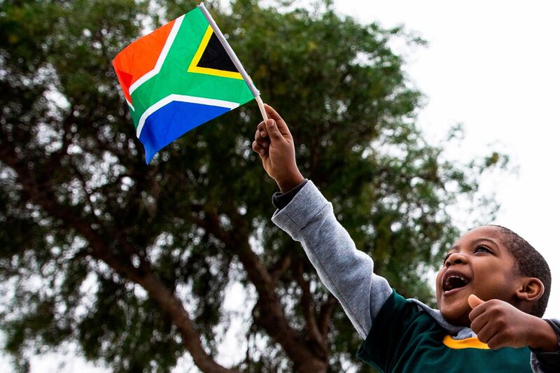 A young Springboks supporter, wearing a jersey with the South African Rugby captain Siya Kolisi's name written on, waves a South African national flag as the South African Rugby World Cup winner team parades on an open top bus. AFP