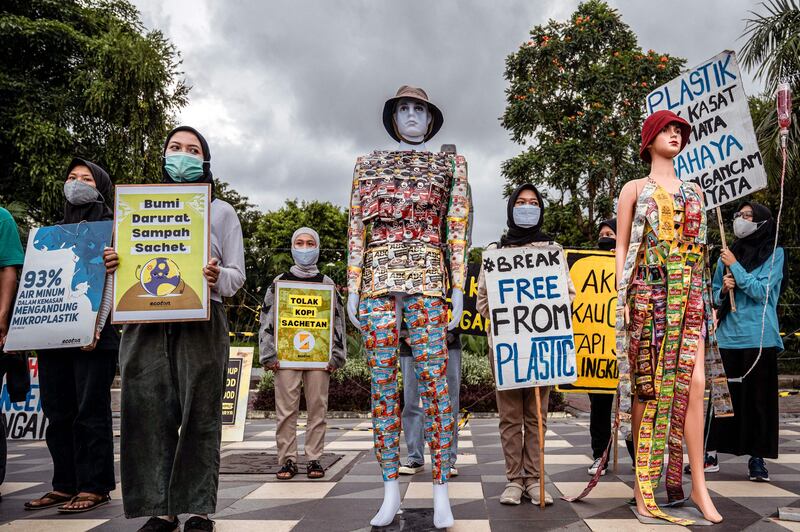 Environmental activists display placards next to mannequins dressed with plastic waste during a campaign against climate change to mark 'Earth Day' in Surabaya, Indonesia. AFP