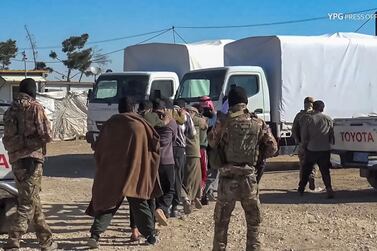 An image grab from a video made available on the People's Protection Units' (YPG) Press Office on March 28, 2021, shows Kurdish YPG forces marching-off men towards vehicles during a security operation at the Kurdish-run Al-Hol camp.  AFP/YPG Press Office