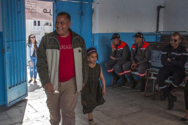 A Tunisian policeman dressed in civilian clothing arrives with his daughter at a polling station for the police and military in Tunis, Sunday, April 29, 2018. This is the first time in Tunisian history that the military and police participate in the voting for the municipal elections, which also the first to be held in the country since the 2011 revolution. (AP Photo/Hassene Dridi)