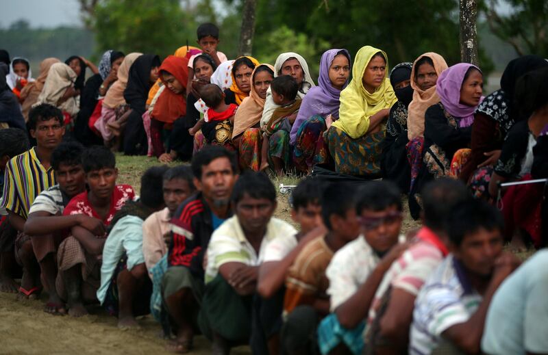 REFILE - CORRECTING DATE Rohingya refugees sit in a line as they wait to receive permission from the Bangladeshi army to continue their way after crossing the Bangladesh-Myanmar border, at a port in Teknaf, Bangladesh, October 31, 2017. REUTERS/Hannah McKay