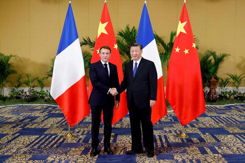 Mr Macron, left, shakes hands with Mr Xi before a meeting between the two leaders. AFP