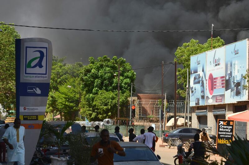 People watch as black smoke rises as the capital of Burkina Faso came under multiple attacks on March 2, 2018, targeting the French embassy, the French cultural centre and the country's military headquarters.
Witnesses said five armed men got out of a car and opened fire on passersby before heading towards the embassy, in the centre of the city. Other witnesses said there was an explosion near the headquarters of the Burkinabe armed forces and the French cultural centre, which are located about a kilometre (half a mile) from the site of the first attack.
 / AFP PHOTO / Ahmed OUOBA