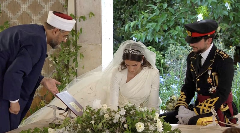 Princess Rajwa signs her marriage certificate as her husband, Prince Hussein, watches. Reuters