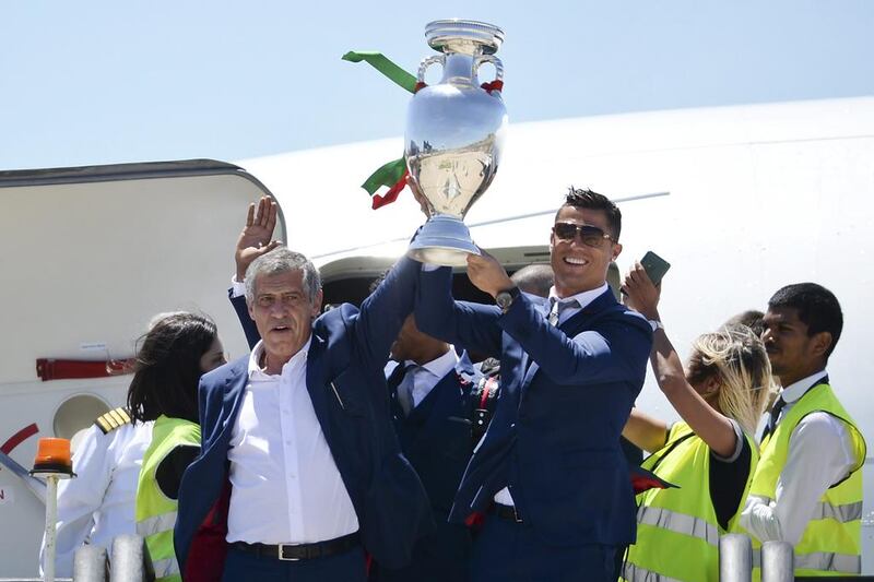 Portugal’s head coach Fernando Santos (L) and Portugal’s forward Cristiano Ronaldo (R) hold the trophy on arrival at Lisbon airport on July 11, 2016 after their Euro 2016 final football win over France yesterday. The Portuguese football team led by Cristiano Ronaldo returned home to a heroes’ welcome today after their upset 1-0 win triumph over France in the Euro 2016 final. AFP / PATRICIA DE MELO MOREIRA