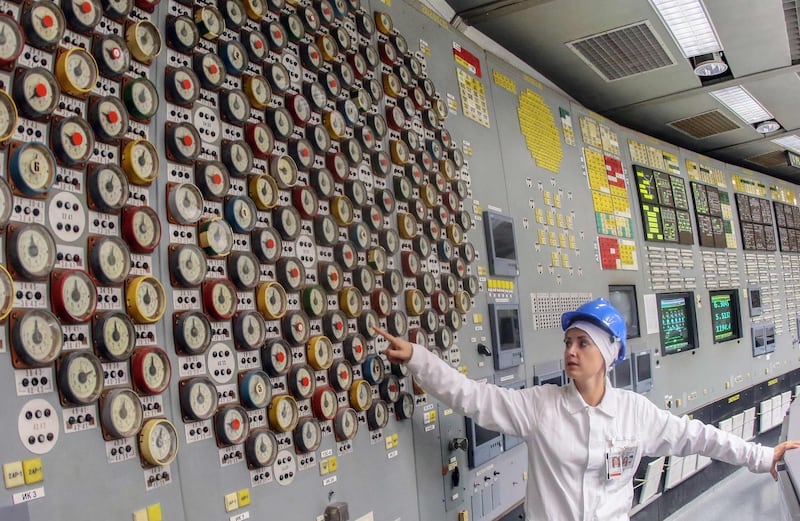 Tour guide Jurgita Norvaisiene points at a measurement device during a guided tour inside the monitoring room of the inoperative Ignalina nuclear power plant.