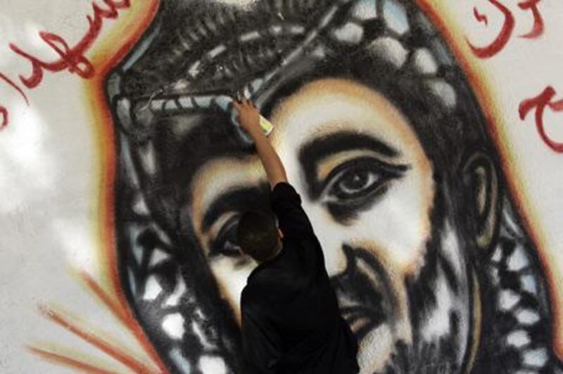 Mohammed Fouad touches up a portrait of Yasser Arafat in Gaza City. "If they see me, I'll go to jail," Mr Fouad says.