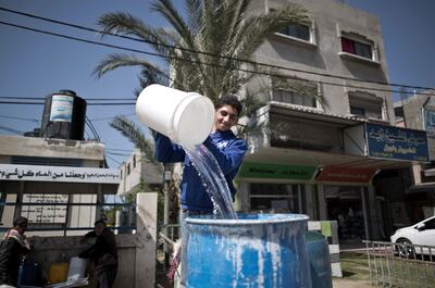 A young Palestinian man fills a container with drinking water in the northern Gaza Strip.  AFP