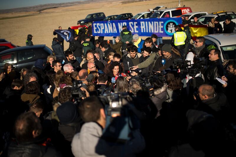 Esquerra de Catalunya (ERC) party candidate Marta Rovira, centre, talks to journalists during a party campaign act in Estremera prison, where former vice president of Catalan regional government Oriol Junqueras is currently jailed, in Estremera central Spain, Tuesday, Dec. 19, 2017. Voters go to polls this week in Spain's northeastern region of Catalonia in elections called by the Spanish government after it sacked the former regional cabinet and dissolved the local parliament. At the back a dozen of pro-Spain activists hold up a blue banner reads in Spanish: "Spain does not give up". (AP Photo/Francisco Seco)
