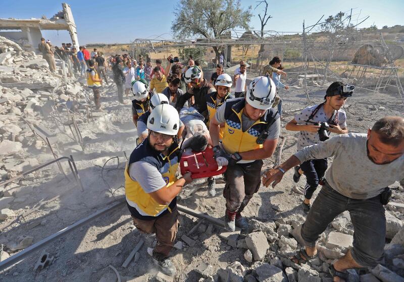 EDITORS NOTE: Graphic content / Members of the Syrian civil defence, known as the White Helmets, carry away on a stretcher a victim who was pulled out of the rubble of a collapsed building following reported air strikes by pro-regime forces on Maaret al-Numan in Syria's northwestern Idlib province on July 23, 2019.   / AFP / Omar HAJ KADOUR
