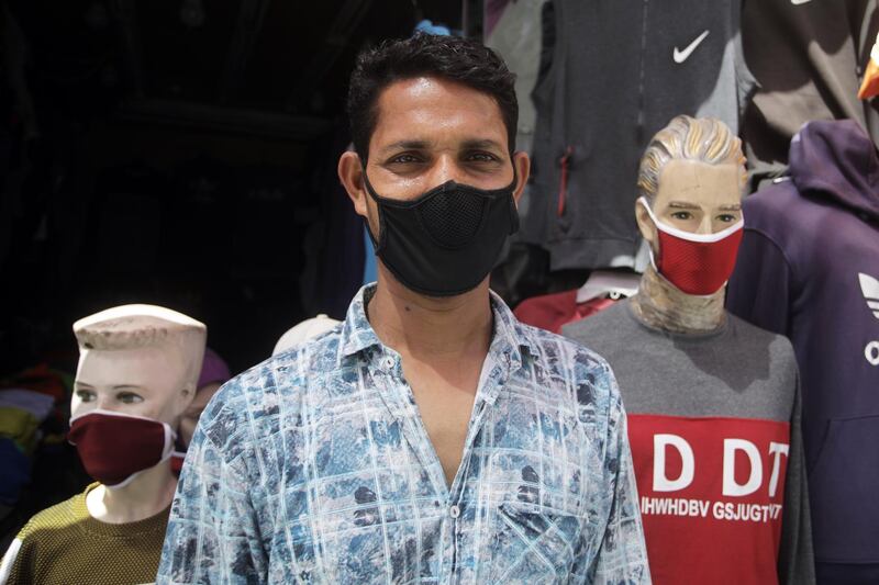 A man wearing a protective face mask stands next to mannequins in a street of Manama, Bahrain. EPA