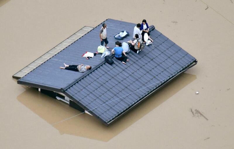 People wait to be rescued on the top of a house almost submerged in floodwaters caused by heavy rains in Kurashiki, Okayama prefecture, southwestern Japan. Shingo Nishizume/AP Photo