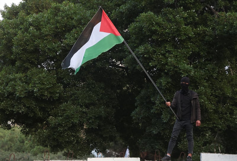 A man holds a Palestinian flag as mourners gather during the funeral. Reuters
