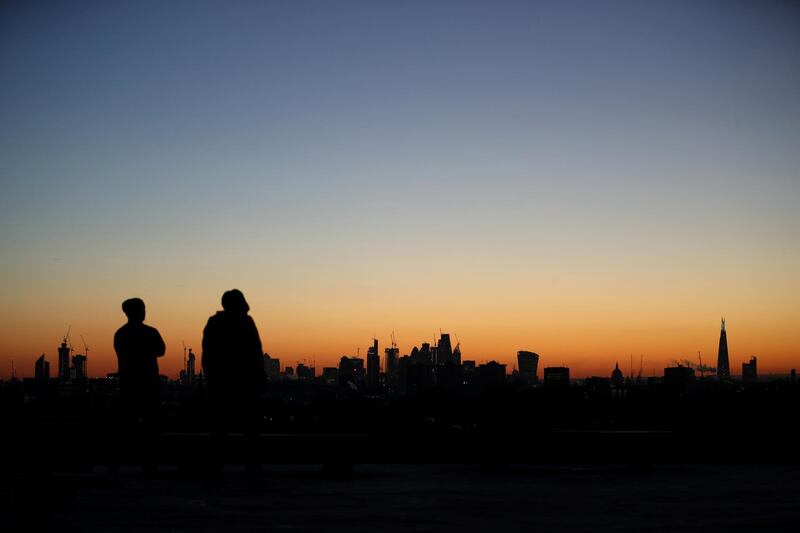 People watch the sun rise behind the Shard and the City of London from Primrose Hill in London. Hannah McKay / Reuters