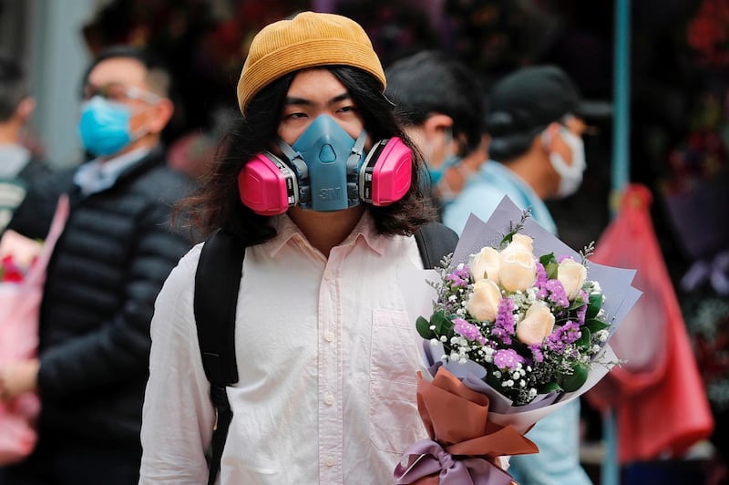 A man wears a gas mask as he holds a bouquet of flowers on Valentine’s Day in Hong Kong. Reuters