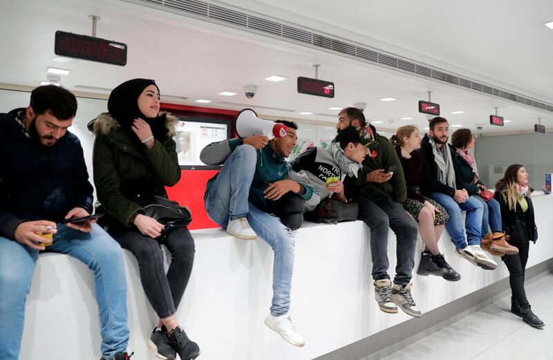 Lebanese protesters occupy a branch of BLC Bank in Beirut on December 28, 2019 in protest against nationwide imposed restrictions on dollar withdrawals and transfers abroad in an attempt to conserve dwindling foreign currency reserves. A liquidity crunch has pushed Lebanese banks to impose capital controls on dollar accounts, capping withdrawals at around $1,000 a month. Some have imposed even tighter restrictions. Some have also capped weekly withdrawals of the Lebanese pound at one million -- the equivalent of $660 at official rates -- even as the currency has plunged by nearly a third against the dollar on the black market in recent weeks.
 / AFP / ANWAR AMRO
