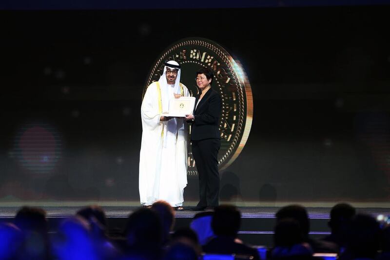 Sheikh Mohammed bin Zayed, Crown Prince of Abu Dhabi and Deputy Supreme Commander of the Armed Forces, presents a representative of<a href="http://www.thenational.ae/uae/environment/zayed-future-energy-prize-award-winner-at-forefront-of-chinas-renewable-revolution---video"> Li Jungeng, the Lifetime Achievement Award winner, </a>with his award since he was unable to attend the event. Delores Johnson / The National