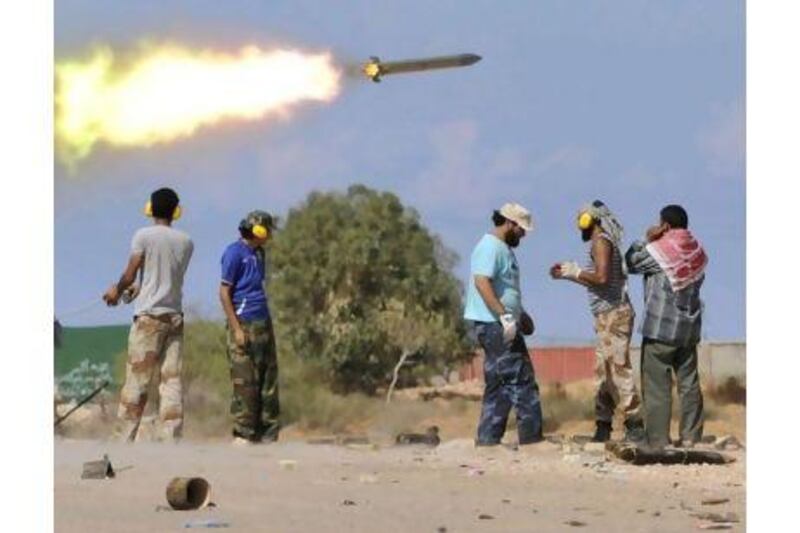 Libyan revolutionary fighters fire a missile during an attack on the city of Sirte yesterday. Bela Szandelszky / AP Photo