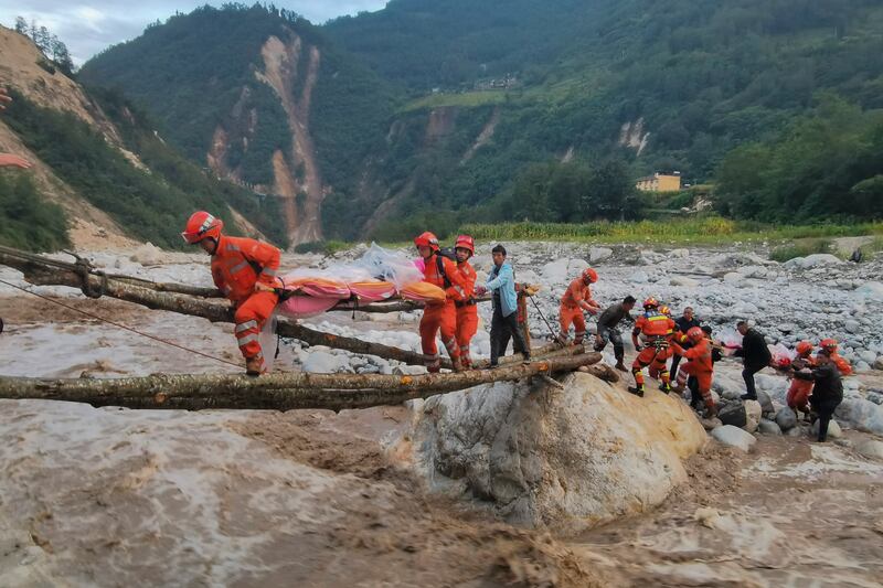 Survivors are helped across a river by rescuers after the quake. AP