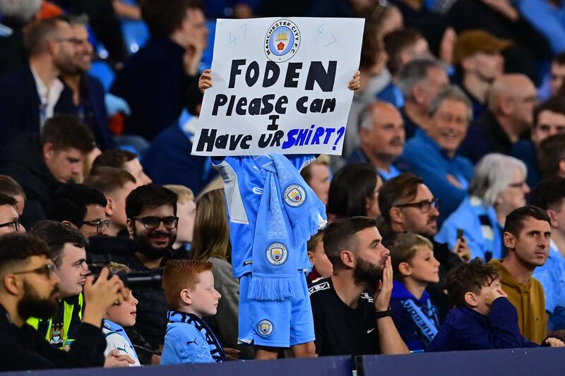 A Manchester City fan holds a sign asking for the shirt of midfielder Phil Foden during a League Cup match. AFP